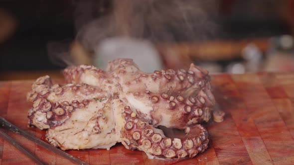 Cinematic handheld shot around a smoking hot half cooked boiled fresh pacific octopus with vaporized