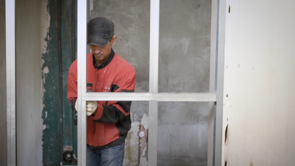 Construction Worker Is Working with a Metal Profiles.