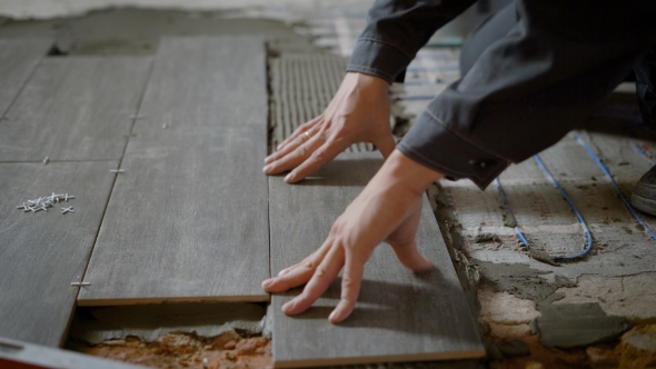 Shot of a Construction Worker Laying Ceramic Tile on the Levelled Floor in the Flat