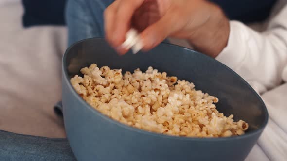 Close-up Shot of a Man's Hand Taking Popcorn From a Bowl While Watching TV.