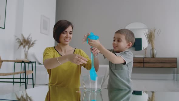 Laughing Mother and Son Spend Time Together Playing at Home in the Apartment