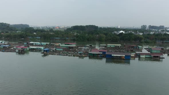 Flying in over floating fish farming community in Bien Hoa on the Dong Nai river, Vietnam on a sunny