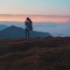 Young Fit Woman in a Poncho Stands on the Highest Mountain Peak, and Enjoys Bright Sunset - VideoHive Item for Sale