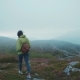 Young Attractive Woman in a Tourist Wear with a Backpack Wanders in the Mountains, Looks Around - VideoHive Item for Sale