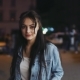 Stylish Young Brunette in Jeans Jacket Walking Down the Night City Street, Looking Right Towards the - VideoHive Item for Sale