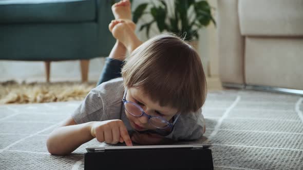 Child Using Tablet Lying on the Floor at Home Distance Learning Elearning Early Child Development