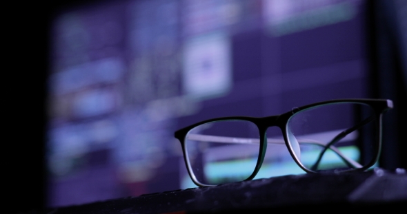 Cyber Attack Concept. Glasses on the Keyboard, on the Background of the Monitor