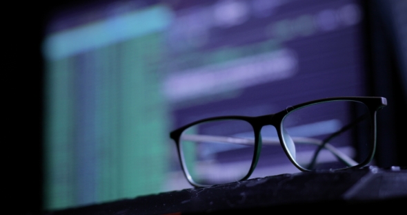 Cyber Attack Concept. Glasses on the Keyboard, on the Background of the Monitor