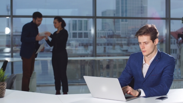 Portrait of Young Attractive Businessman Working at a Desk, Use Laptop in the Office