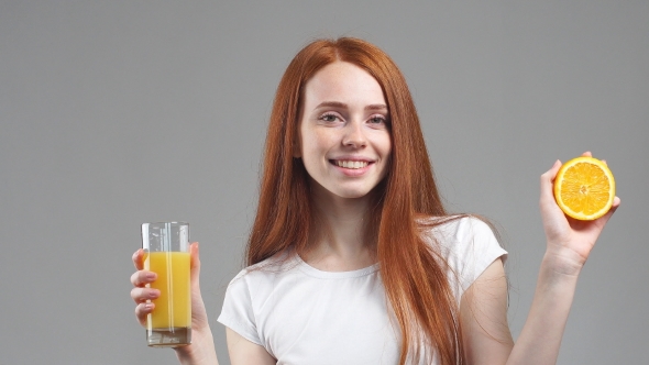 Girl Holding Glass of Orange Juice and Laughing at Camera