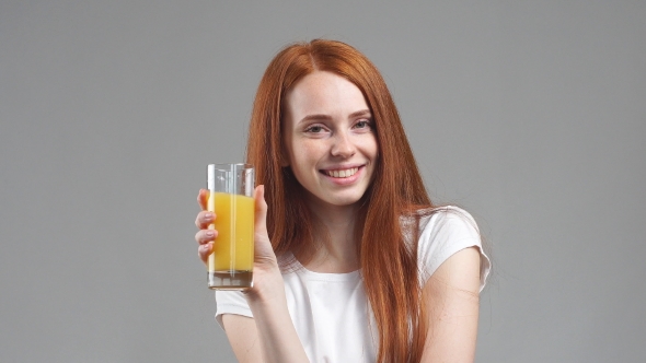Girl Holding Glass of Orange Juice and Laughing at Camera.