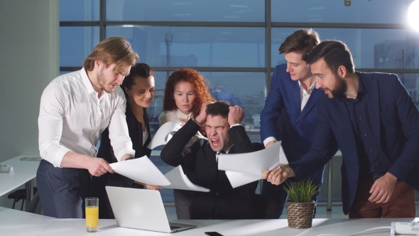 Businessman Under Stress at Work. Colleagues Shaking Papers in His Face.