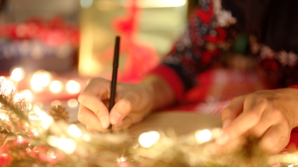 Hands Writing Christmas Letter To Santa Claus on Christmas Eve