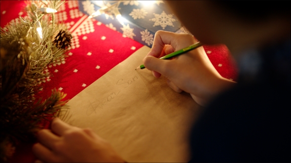 of Female Hands Writing Christmas Letter with Her Wishlist on New Years Night