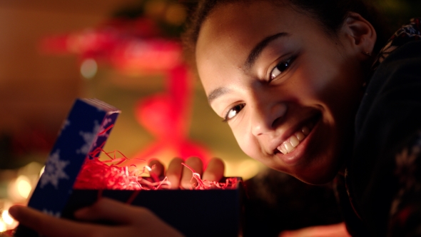 Young Woman Openning Cristmas Gift and Smiling on New Years Night