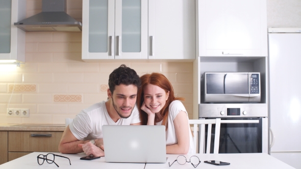 Young Business Couple Working with Laptop at Home in Kitchen.