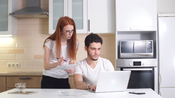 Business Couple with Tablet Computer and Bills in Kitchen at Home.