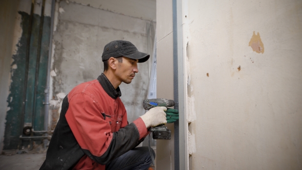 Man Using Tool Fixing Overlaps on Wall in Building alt
