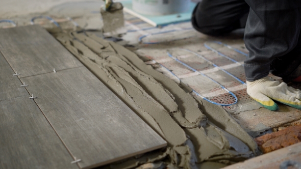 Professional Constructor Applying Cement on Floor and Laying Ceramic Tiles