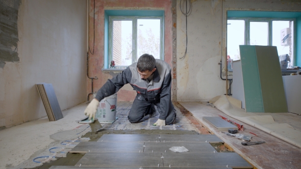 Builder Decorating Floor of Spacious Room Under Construction Arranging Tiles