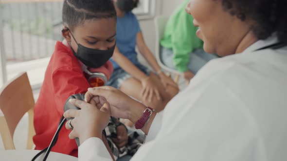 African american doctor is measuring blood pressure and checking pulse child patient.