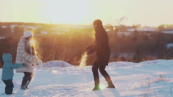 Happy People Play Snowballs on White Snowy Ground in Evening
