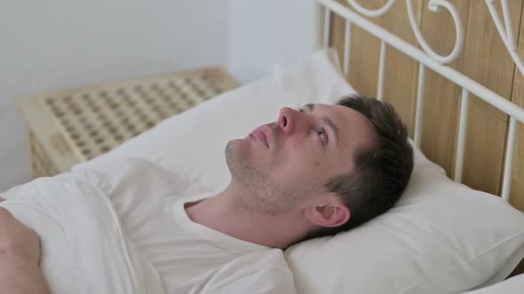 Thoughtful Young Man Awake in Bed Thinking