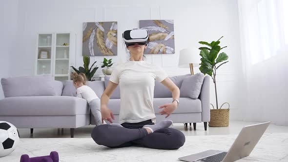 Young Mother which Doing Yoga Exercises  in Lotus Pose Using Augmented VR Glasses