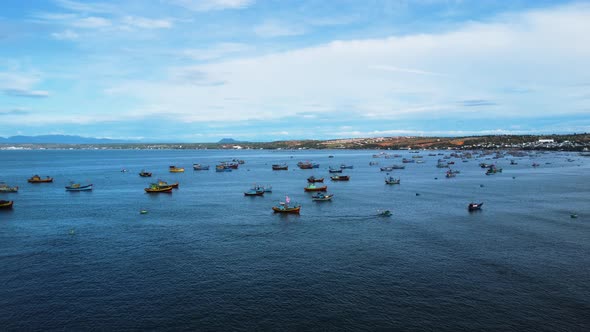 Aerial shot of a beautiful scene with hundreds of colorful fishing boats in the blue sea and distant