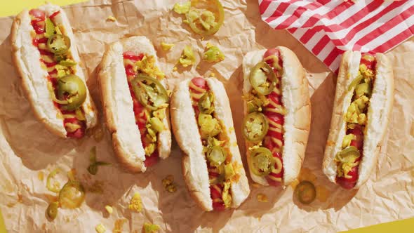 Video of hot dogs with mustard, ketchup and jalapeno on a yellow surface