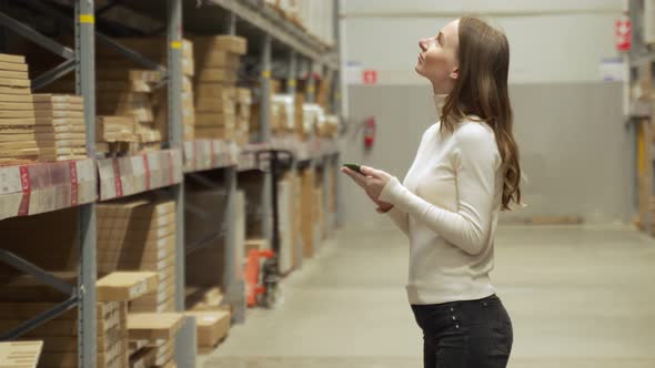 Woman Worker Using Smartphone to Checking Inventory in Warehouse Store