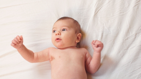 Happy Newborn Baby in White Bed.