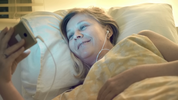 Before Falling Asleep a Woman Wishes a Good Night To a Loved One Via the Internet Using a Smartphone