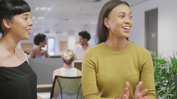 Diverse female business colleagues talking and smiling in office