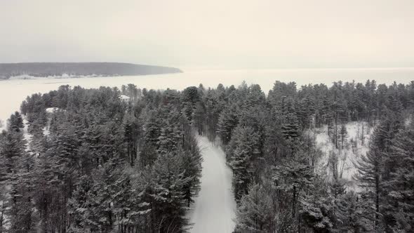 Aerial View Winter Landscape on a Snowy Cloudy Day of a Fairy Forest and a Frozen Winter Lake