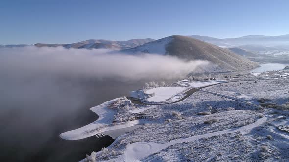 Aerial view flying over snow covered landscape next to lake