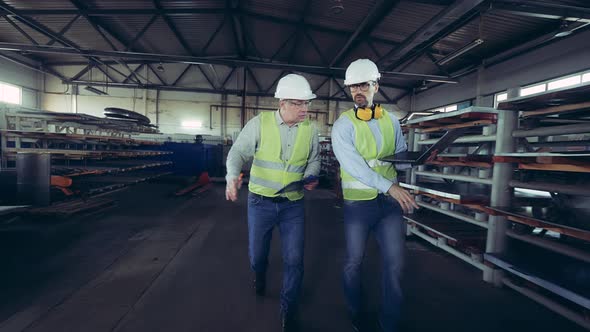Male Inspectors Are Walking Along the Metal-factory Warehouse