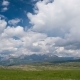 Clouds Over the Green Meadow with Majestic Mountains in the Background - VideoHive Item for Sale