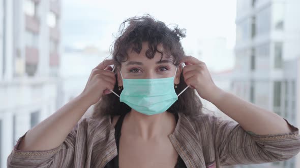 Young woman putting on surgical mask.