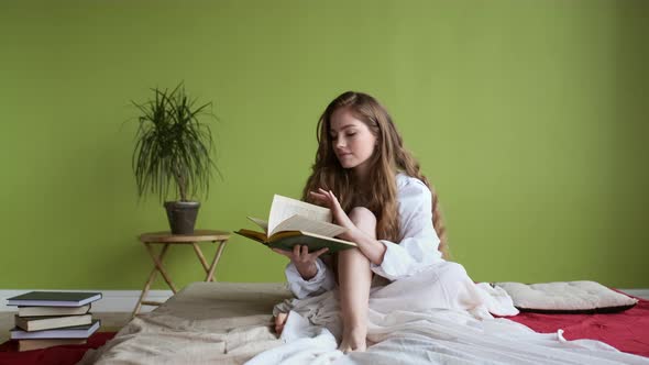 Girl Sitting On The Bed And Reading Book