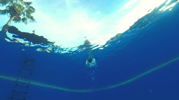 A Man Jumps Into the Pool and Swims in Front of the Camera