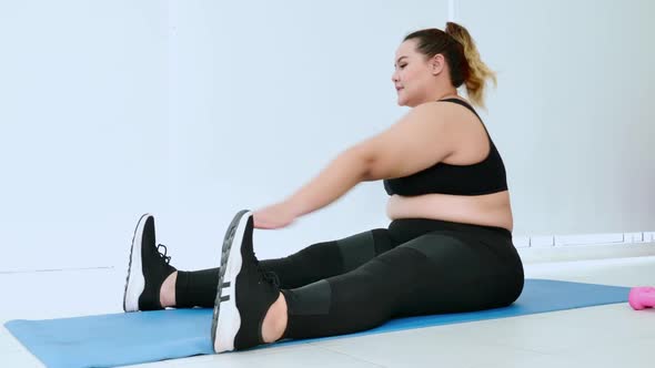 Overweight young woman in sportswear exercising at home