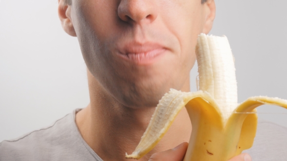 of Young Man Eating a Banana on a White Background