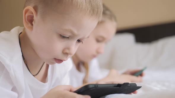 Cute Girl and Sweet Boy Playing in Video Game on Two Smartphones