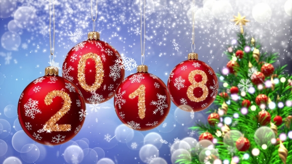 Red Balls with Numbers 2018 Hanging on the Background of a Blue Bokeh and a Rotating Christmas Tree