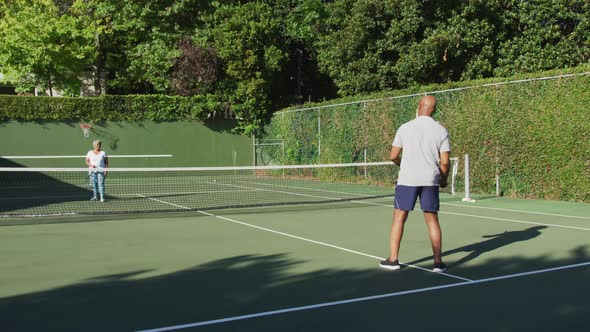 African american senior couple playing tennis on the tennis court on a bright sunny day