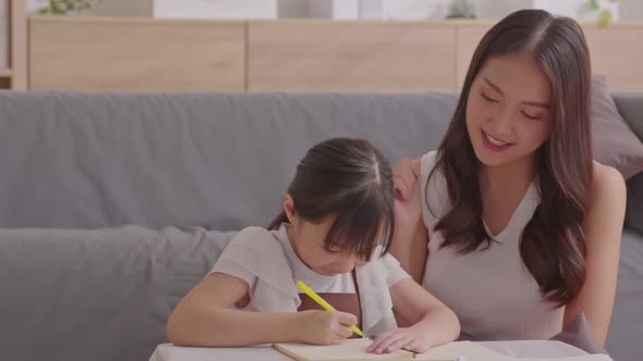 Happy asian young mother smile with daughter in living room at home