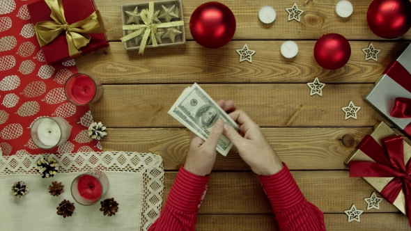 Man Counts Dollars By Christmas Decorated Table, Top Down Shot