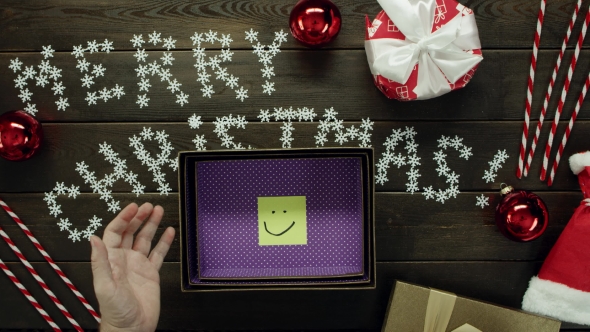 Top Down Shot of Adult Man Opening Xmas Gift with Sticky Note with Smile Inside