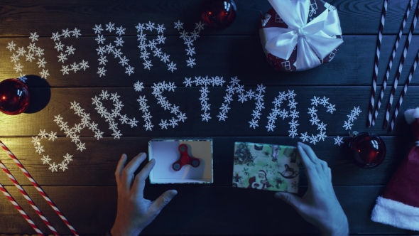 Man Opening New Year Present with Fidget Spinner Inside, Top Down Shot